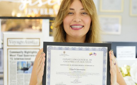 The founder of Yisel Jewelry smiling and holding a certificate of recognition
